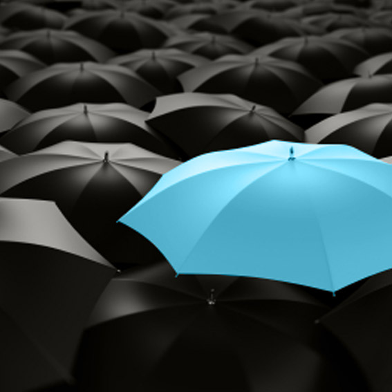Blue umbrella in sea of black umbrellas.